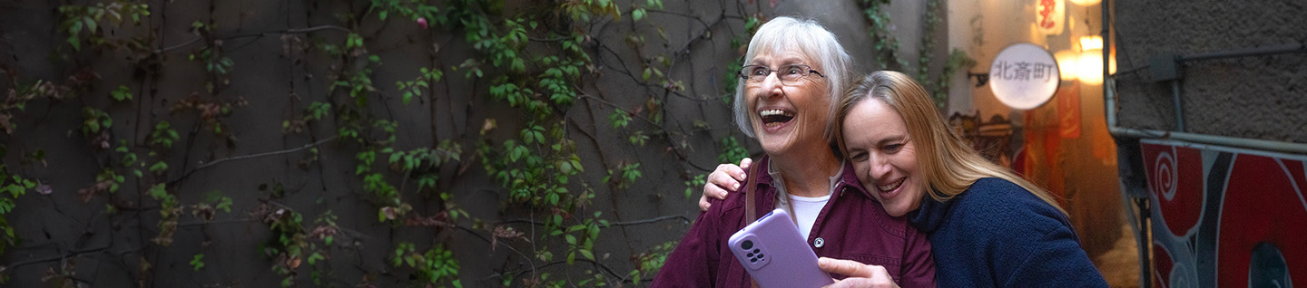 Two women laughing while looking at a phone
