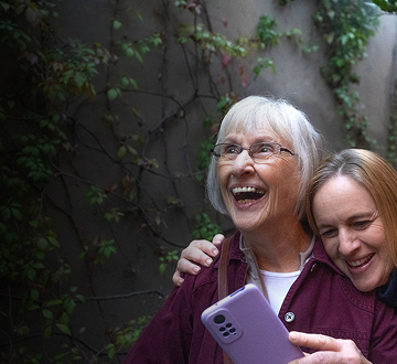 Two women laughing while looking at a phone