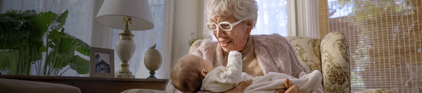 Elderly woman sitting in a chair holding a baby