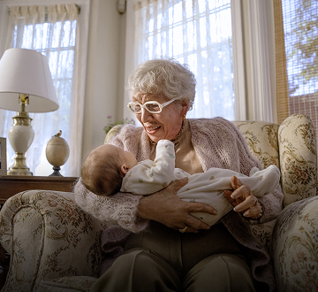 Elderly woman sitting in a chair holding a baby