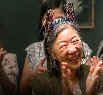 Elderly woman celebrating her birthday with people clapping around her